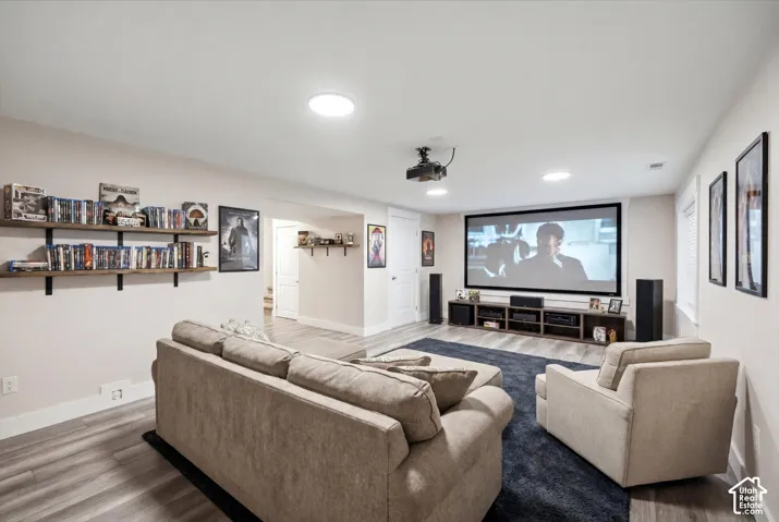 Dedicated media room featuring a large projection screen, recessed lighting, and wood-finish flooring