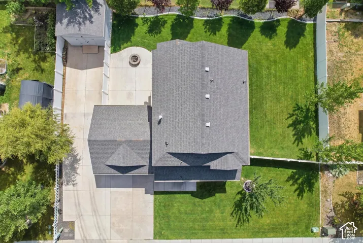 Aerial perspective highlighting a spacious backyard with a manicured lawn, paved patio featuring a built-in fire pit, and privacy fencing