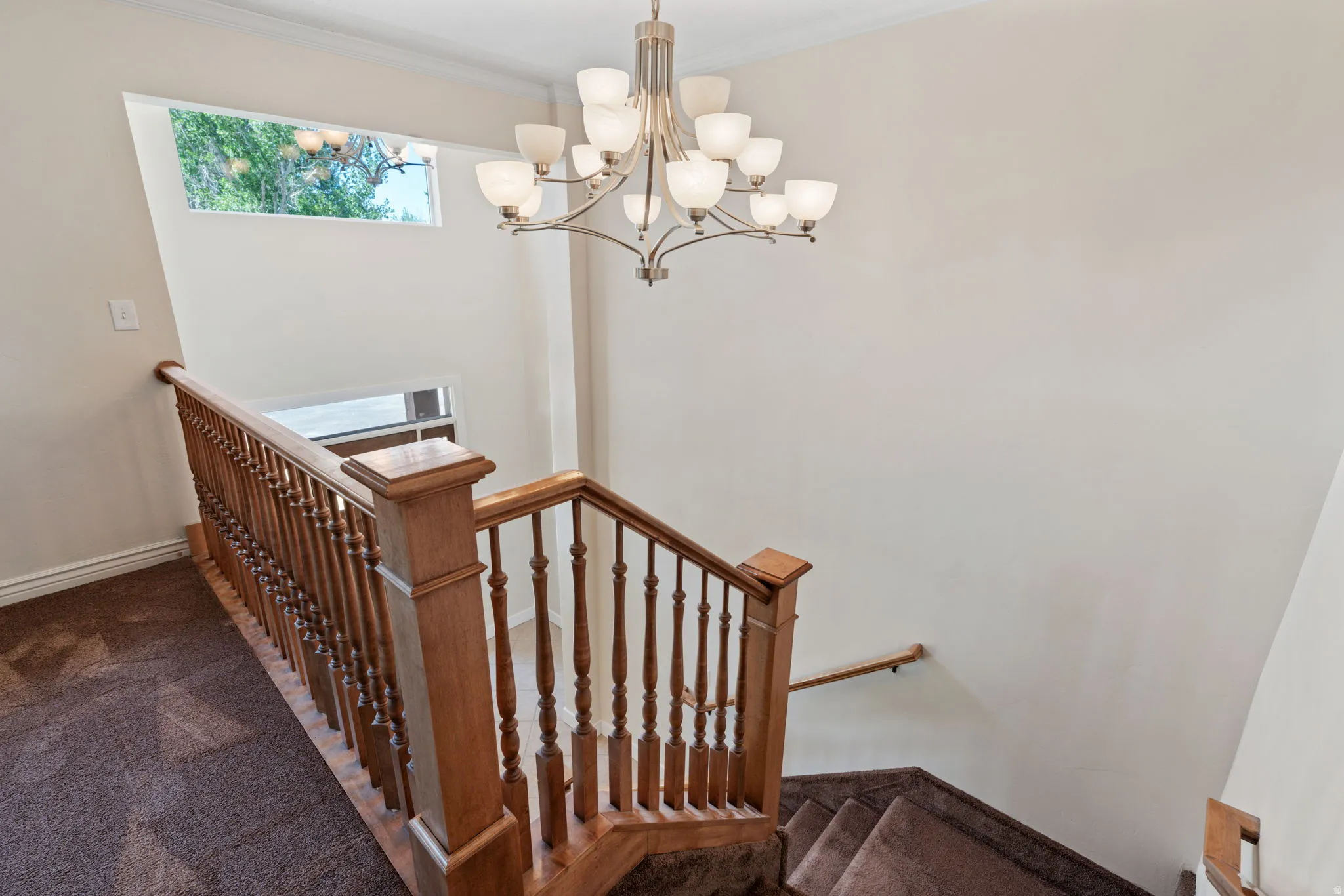 Staircase featuring wood-finish railings and newel posts, complementing the carpeted treads