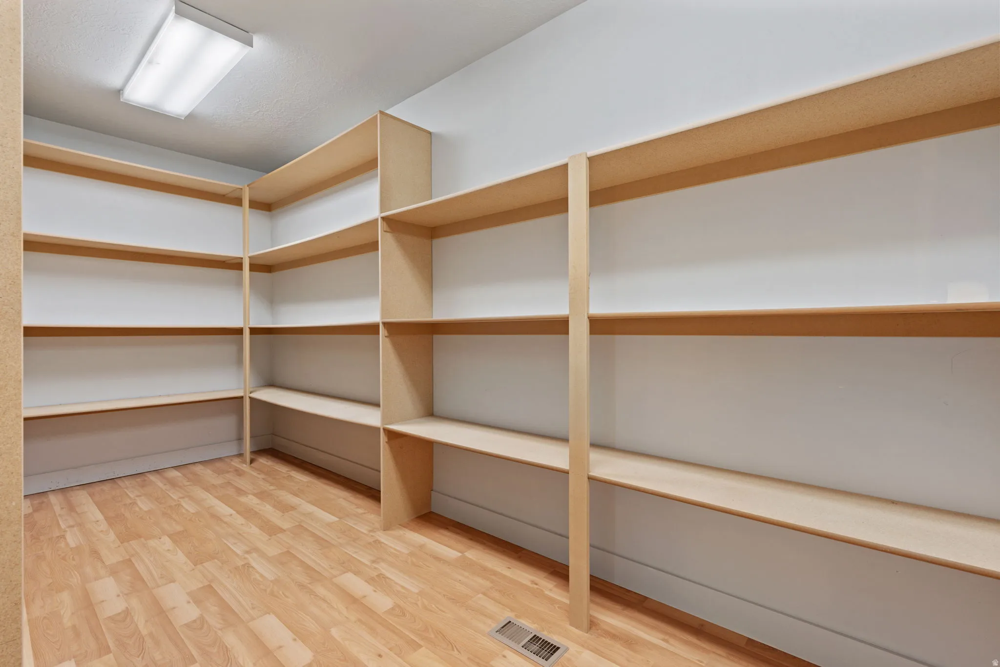 Utility room featuring extensive built-in shelving, wood-finish flooring