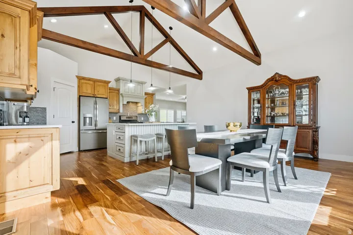 Vaulted ceilings with exposed timber beams define this expansive space, featuring wood-finish flooring throughout