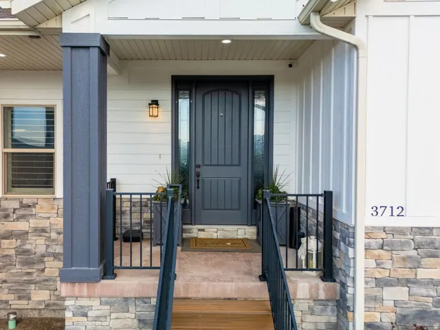 Inviting entryway with a paneled dark gray door, complementary sidelights, and a black exterior light fixture