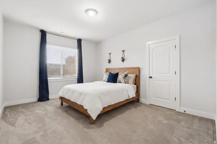 Spacious room featuring neutral carpeting, a large window with blinds, and white trim throughout