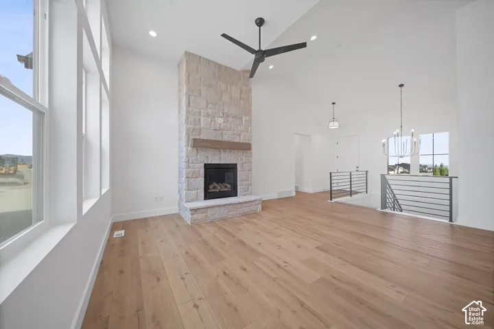 Spacious room featuring vaulted ceilings, a prominent stone-clad fireplace with a wood mantel, and large windows