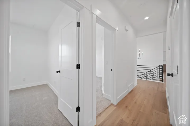 Hallway featuring wood-finish flooring, recessed lighting, and a modern chandelier