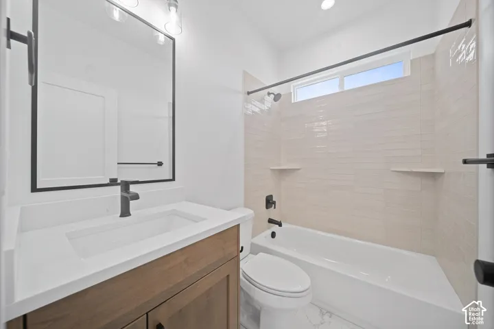 Bathroom featuring a wood-finish vanity with a white countertop and integrated sink, matte black faucet, and framed mirror