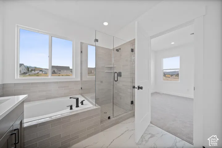 Contemporary bathroom featuring a built-in tub with matte black fixtures, a glass-enclosed shower with tile surround, and a vanity with a light-colored countertop