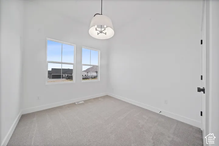 Carpeted room with a vaulted ceiling, two vertical windows, a contemporary drum-shade light fixture, and white baseboards