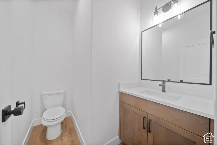 Powder room featuring a wood-finish vanity with an integrated sink, white countertop, and matte black fixtures