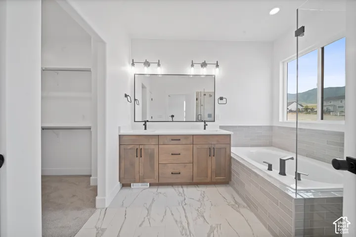 Bathroom featuring a double vanity with wood-finish cabinetry, a large frameless mirror, and modern light fixtures