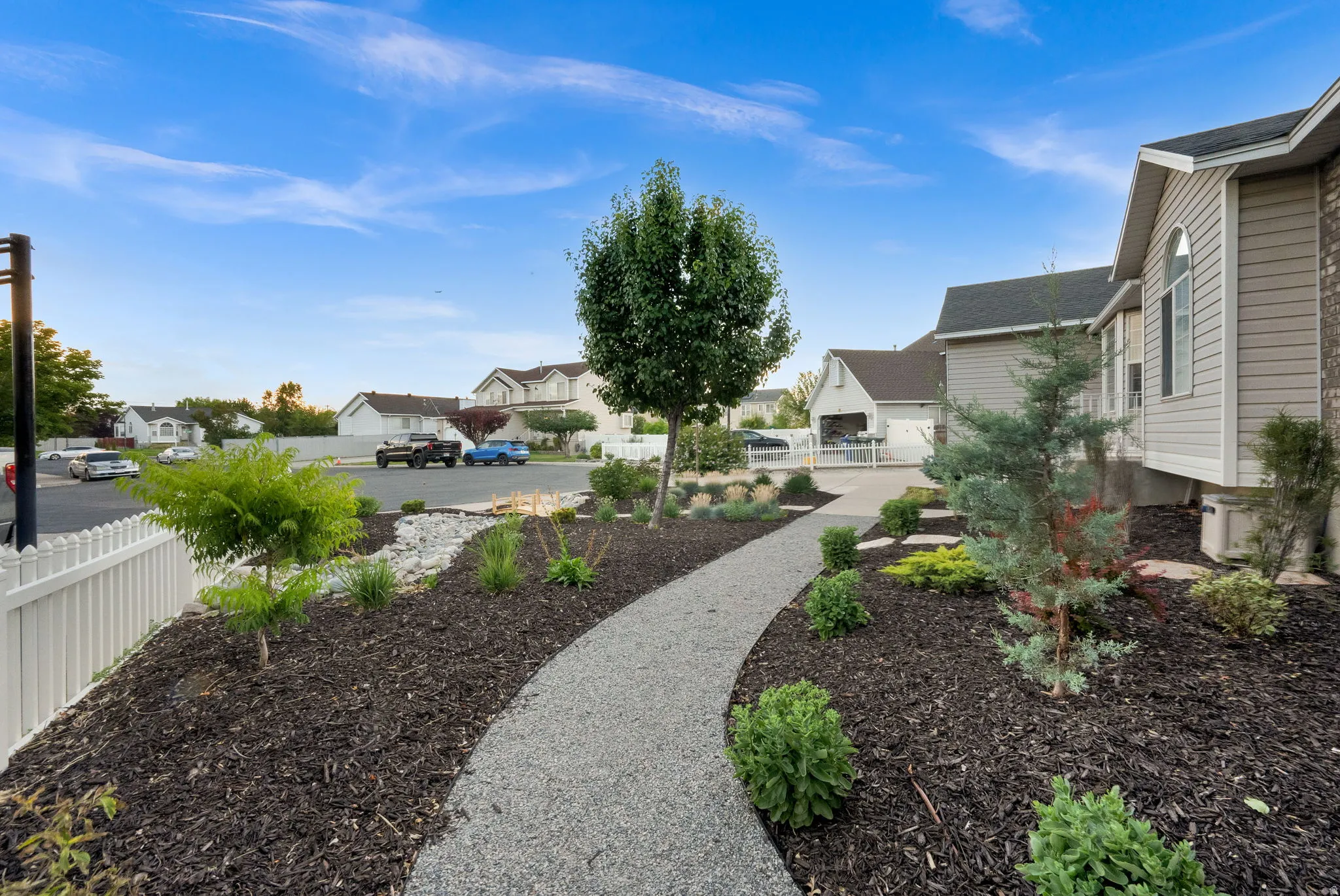Front yard landscaping featuring a gravel pathway, mature trees, and decorative shrubbery