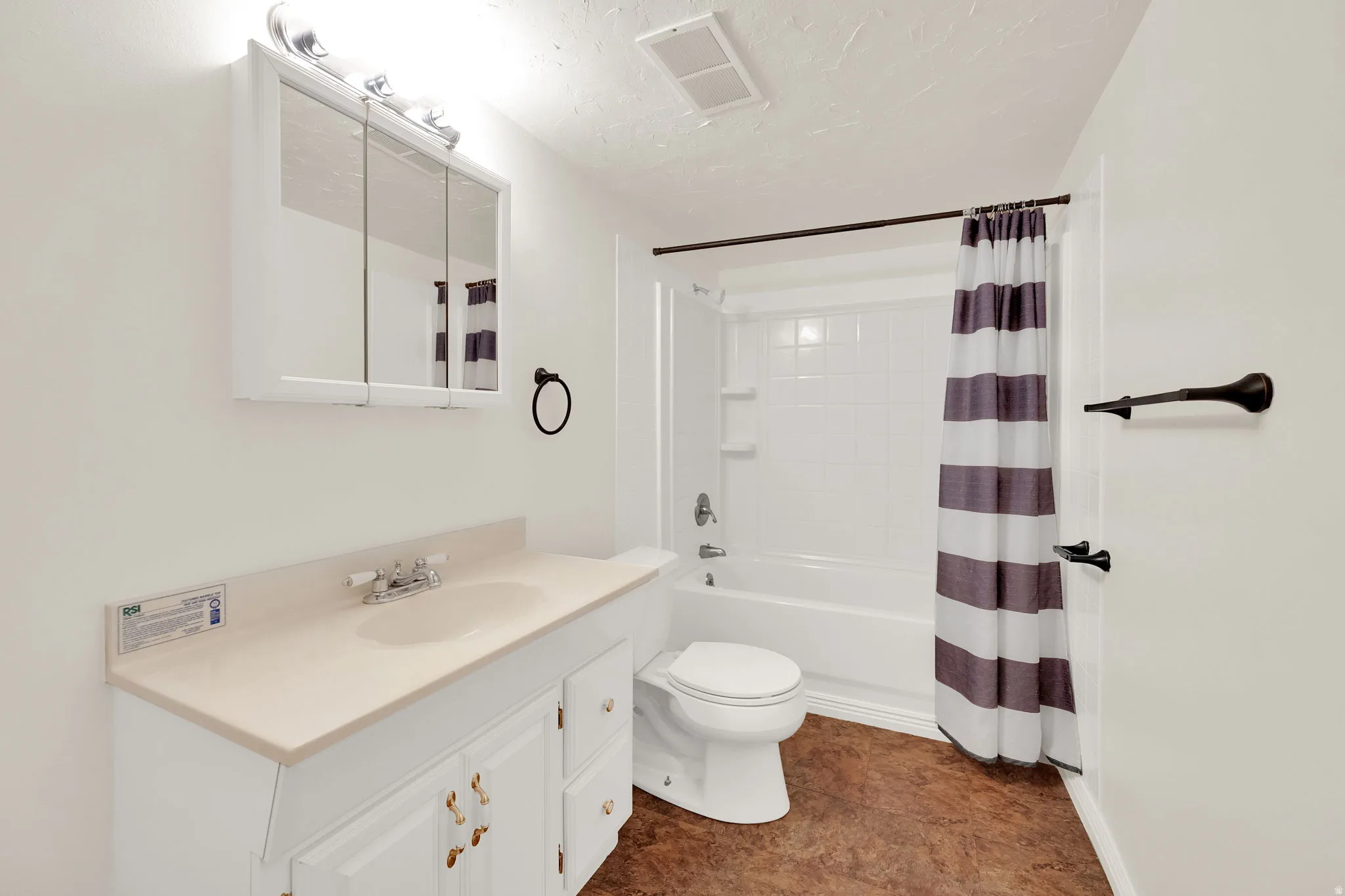 Full bathroom featuring a white vanity with integrated sink, a medicine cabinet with vanity lighting, and a white tub/shower combination