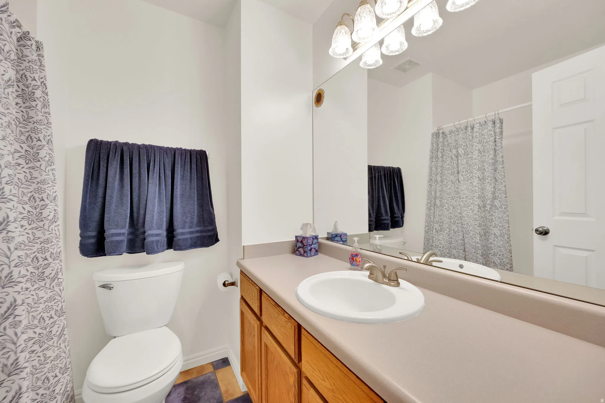 Bathroom vanity with a single basin sink, brushed nickel faucet, and a large mirror with integrated lighting
