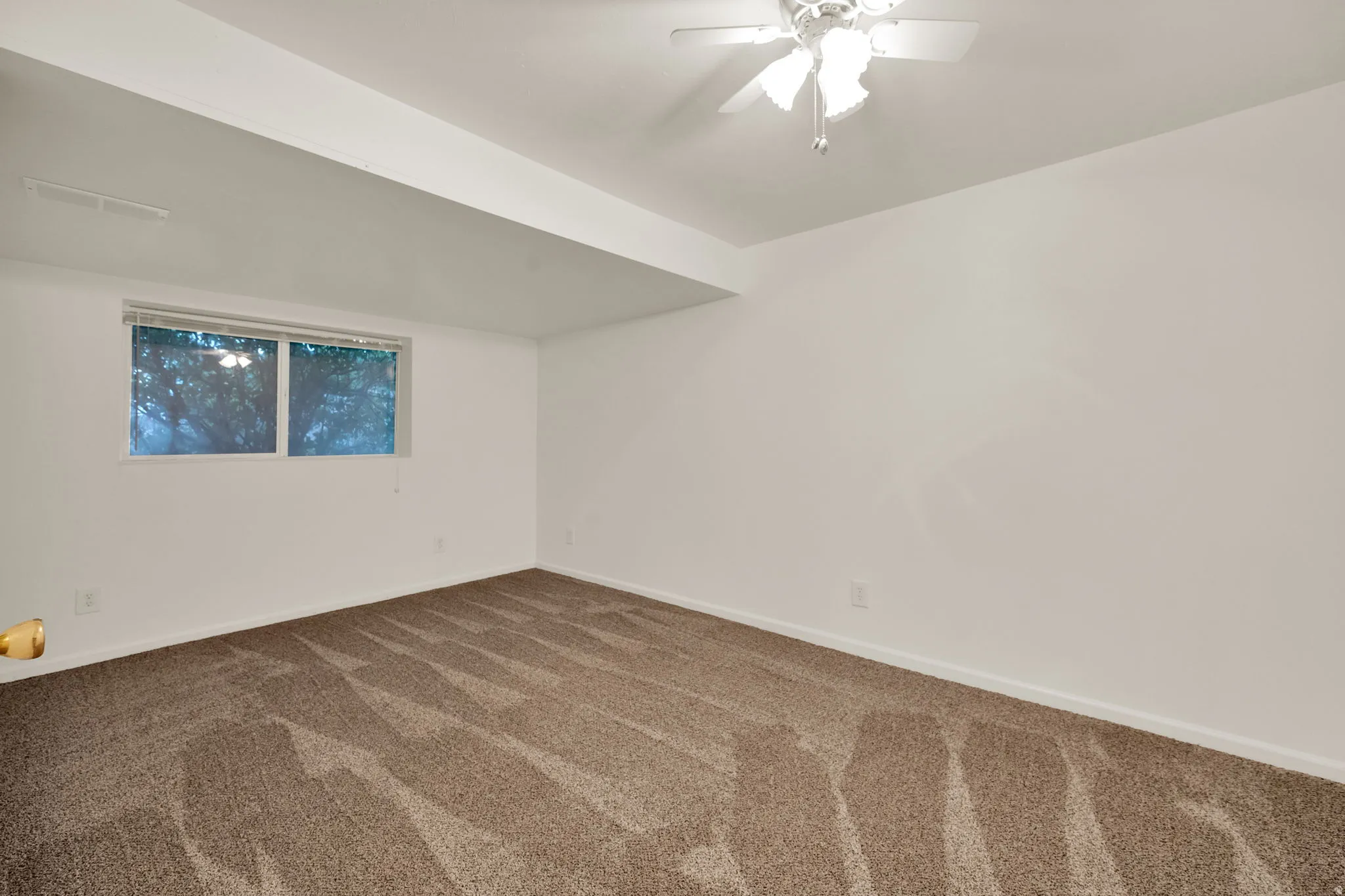 Neutral wall paint with baseboard trim, patterned carpet flooring, and a ceiling fan with integrated lighting