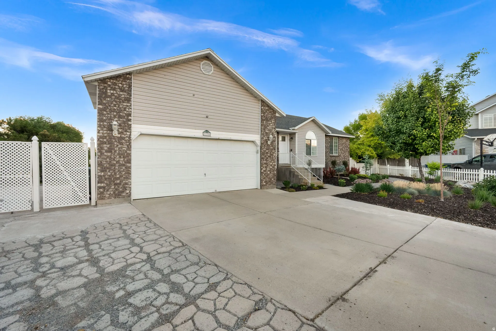 Split-level residence featuring a two-car garage, brick and siding exterior, and a concrete driveway