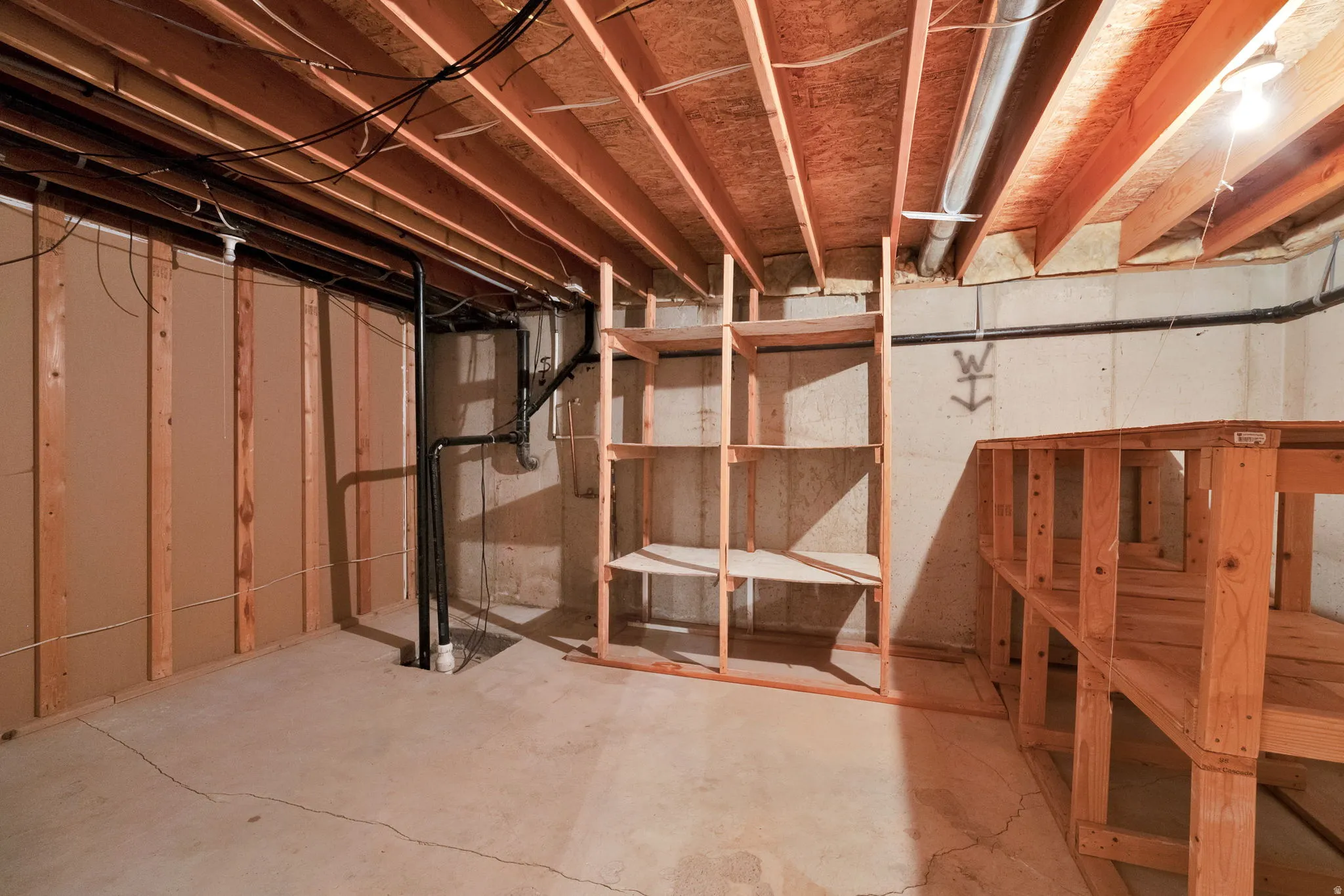 Unfinished basement offering exposed joists, concrete flooring, and partial wall framing