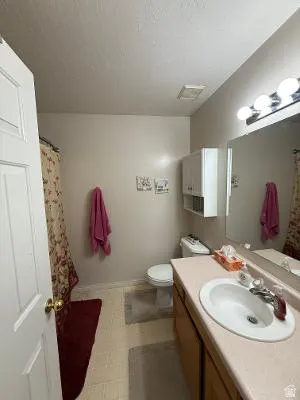 Bathroom featuring a single vanity with a laminate countertop, white basin sink, and chrome faucet