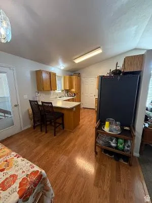 Kitchen featuring wood-finish flooring, light wood cabinetry, white countertops, and a central island with seating