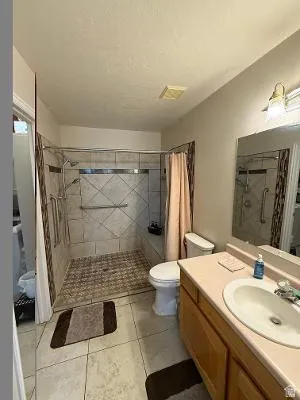 Bathroom featuring a tiled shower with grab bars and a glass enclosure
