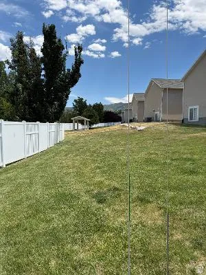 Expansive grassy yard area featuring a white vinyl fence