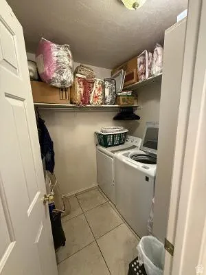 Dedicated laundry area featuring tile flooring and overhead shelving
