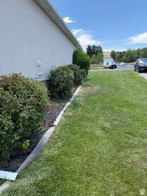 Stucco exterior with a fascia and soffit, complemented by mature shrubbery and a manicured lawn