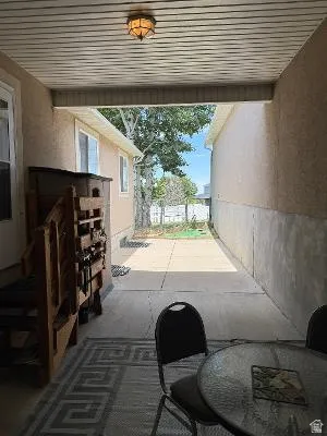 Covered patio featuring a ceiling-mounted light fixture, concrete flooring, and an open side yard with mature trees