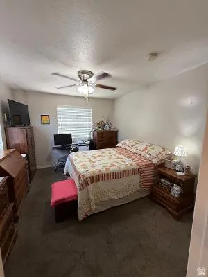 Carpeted room featuring a ceiling fan with integrated lighting, a window with horizontal blinds, and a built-in smoke detector