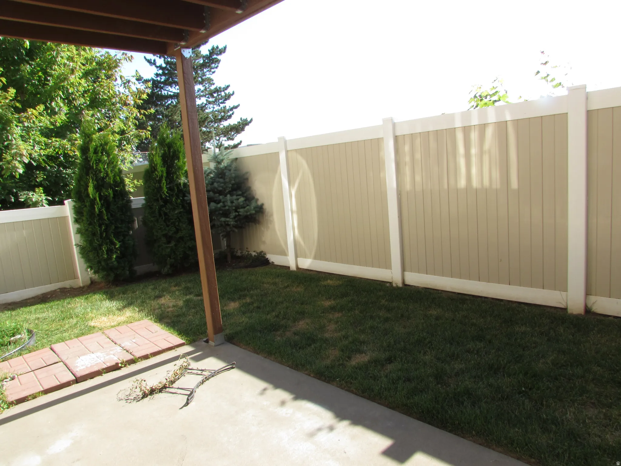 Private outdoor patio featuring a concrete slab and partial brick paver patio