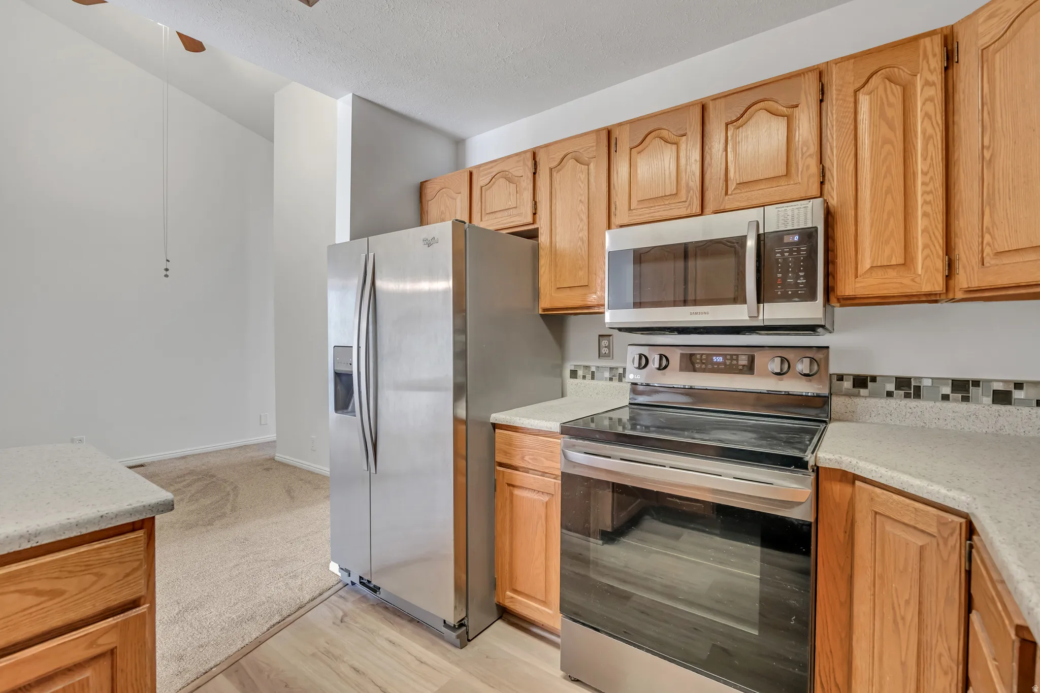 Kitchen featuring wood cabinetry, light-toned countertops, and a mosaic tile backsplash