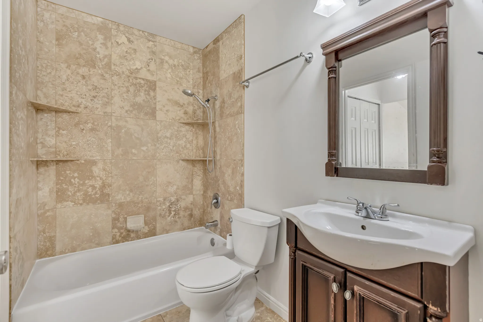 Full bathroom featuring a white tub, shower with built-in niches, vanity with a white basin sink, dark wood-finish cabinet, and a framed mirror