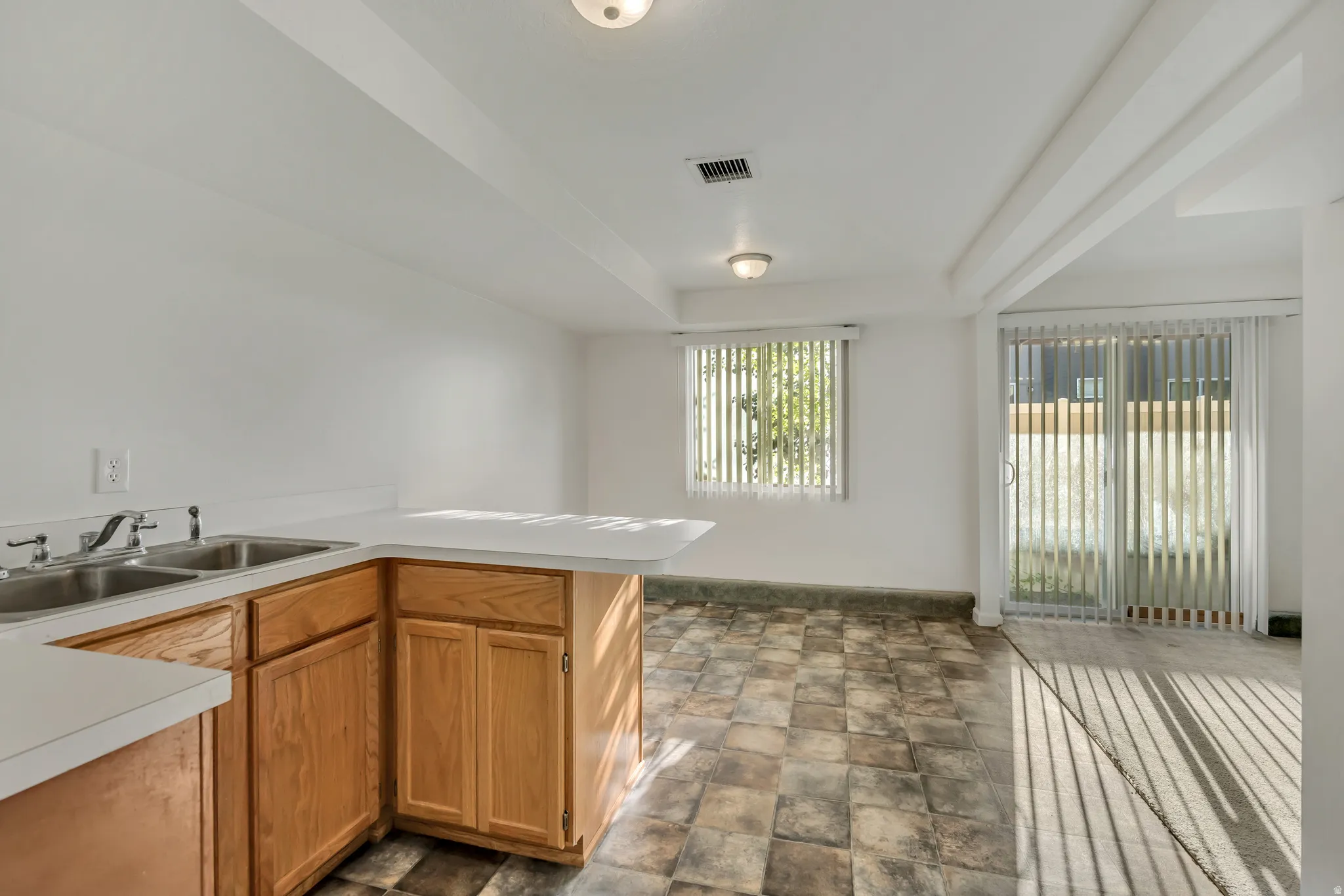 Kitchenette area featuring light wood-finish cabinetry and a double basin sink