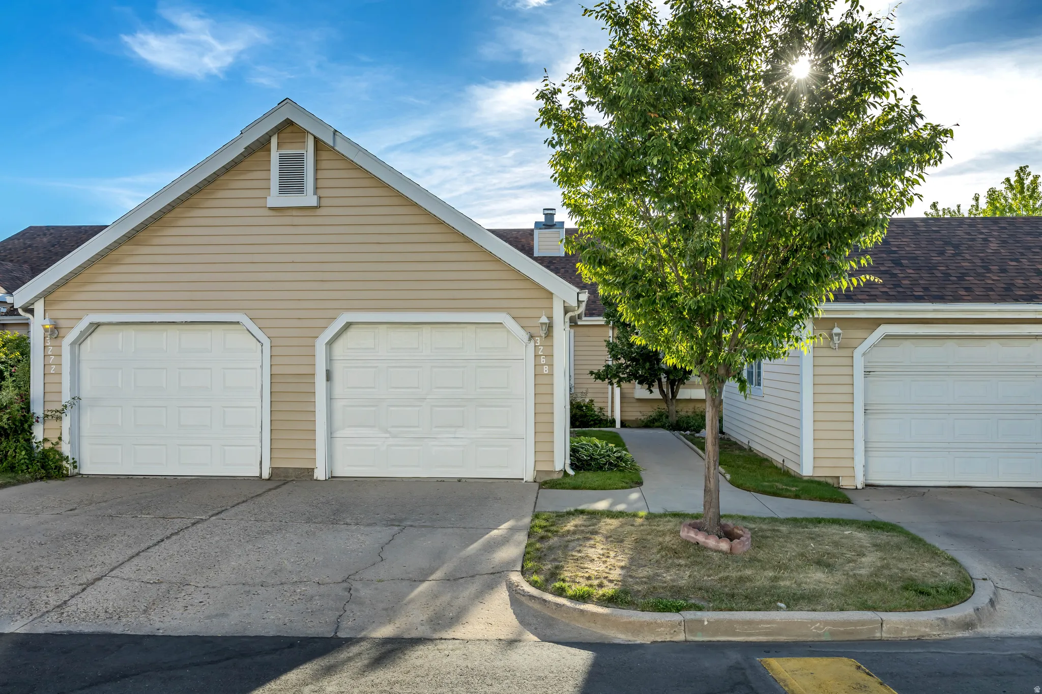 Beige horizontal siding exterior featuring multiple white panel garage doors