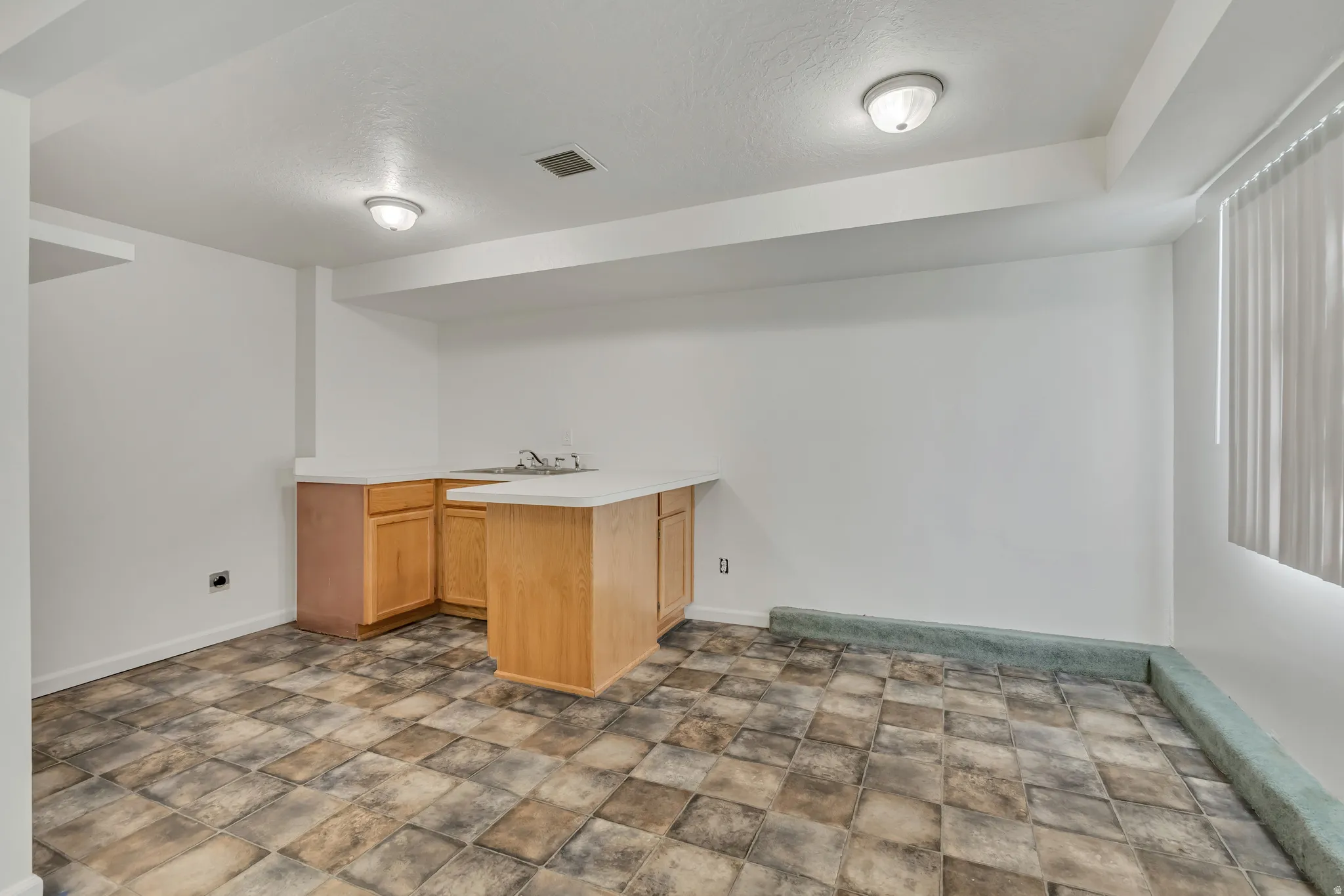 Lower-level room featuring light wood-finish cabinetry  and white countertop
