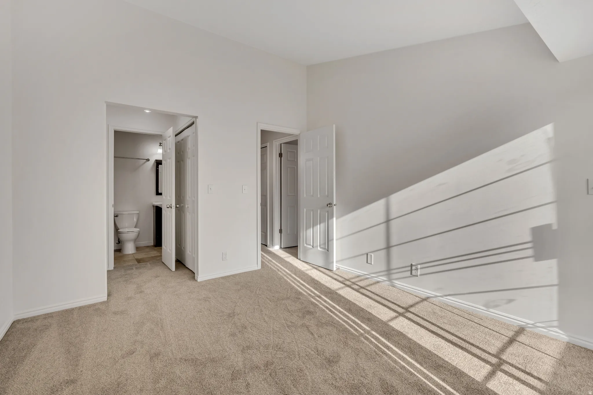 Light-colored carpeted flooring extends throughout this room, featuring white walls and white trim