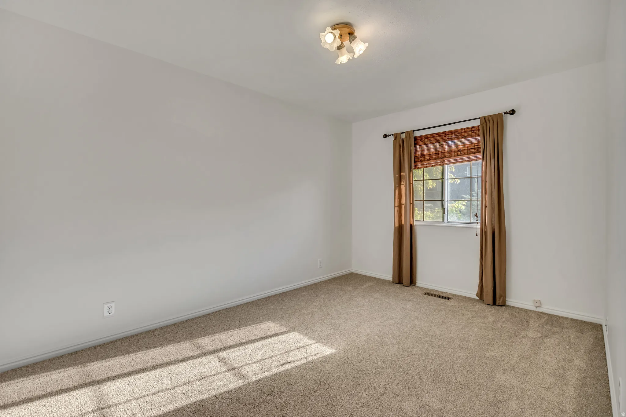Carpeted room featuring a single window and a ceiling-mounted light fixture