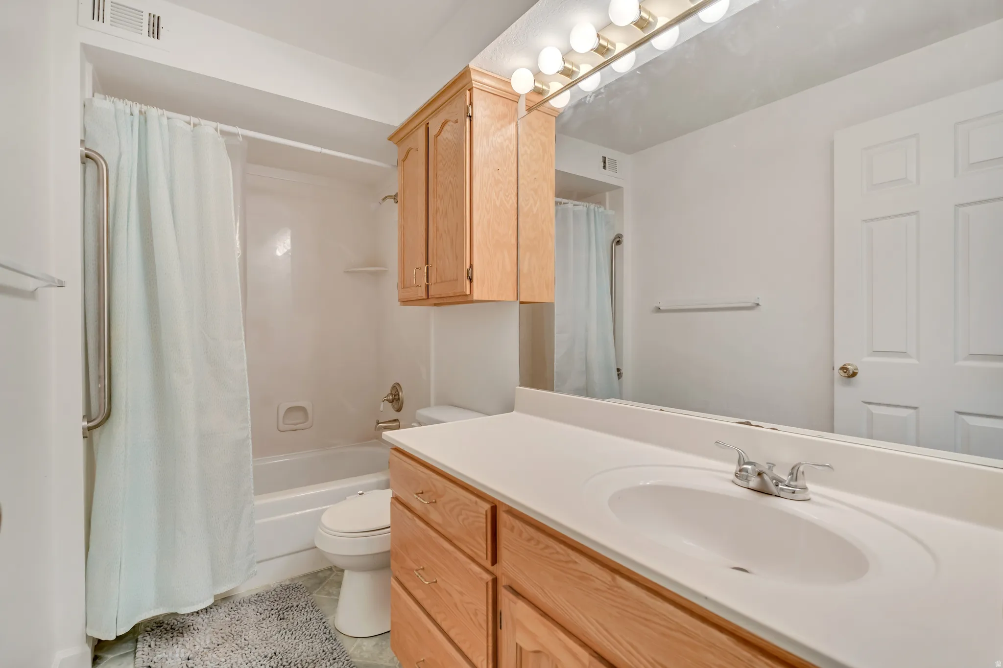 Bathroom featuring a single vanity with a laminate countertop, integrated sink, and wood-finish cabinetry