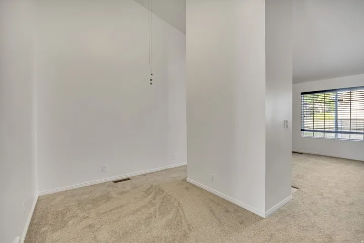Open room featuring vaulted ceilings, light-toned carpeting, and white baseboards