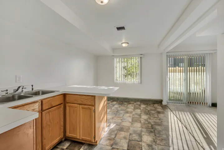 Kitchenette area featuring light wood-finish cabinetry and a double basin sink