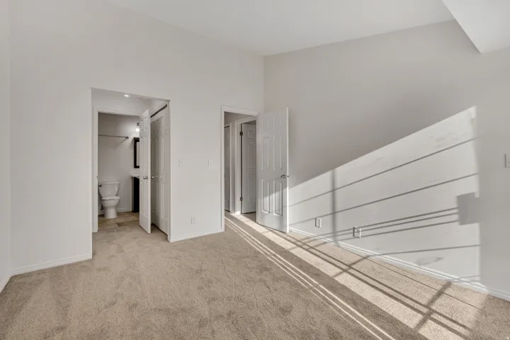 Light-colored carpeted flooring extends throughout this room, featuring white walls and white trim