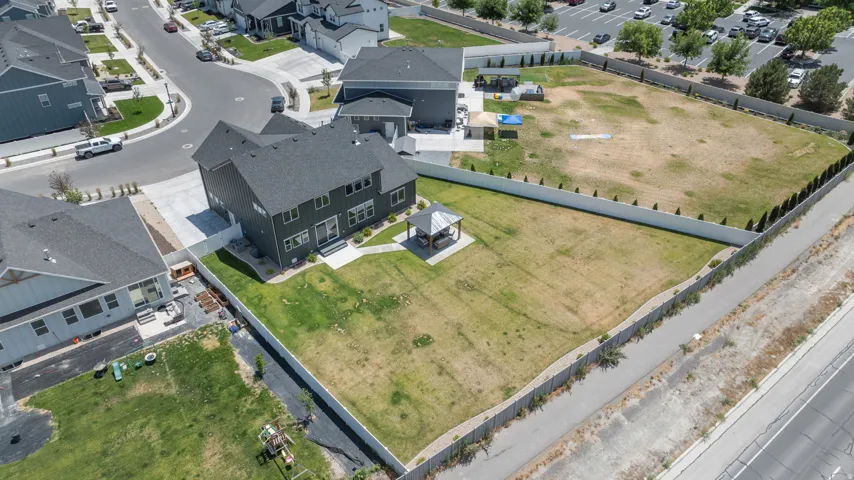 Expansive property featuring a large two-story residence with dark siding and a prominent roofline, a spacious backyard with a gazebo, a concrete patio, and a paved driveway leading to a two-car garage