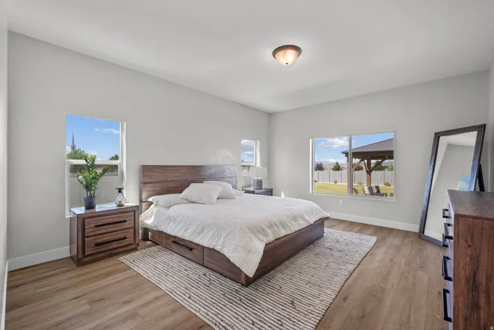 Spacious bedroom featuring light neutral wall paint and wood-finish flooring