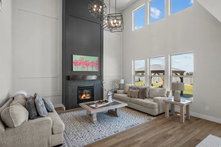 Two-story living area featuring a floor-to-ceiling fireplace with stone surround and wood mantel