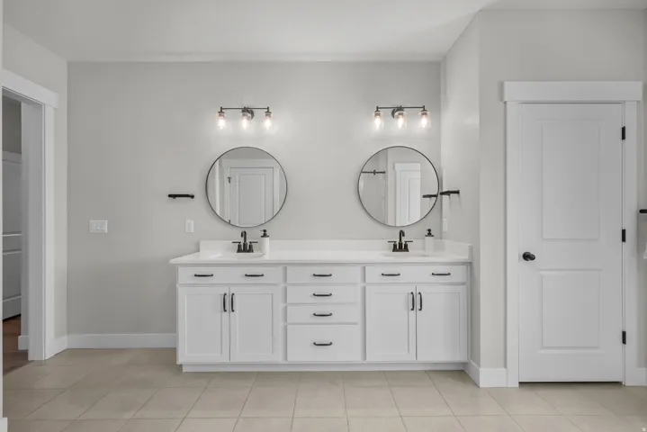 Double vanity featuring white cabinetry with matte black hardware, dual undermount sinks, and a light-toned countertop