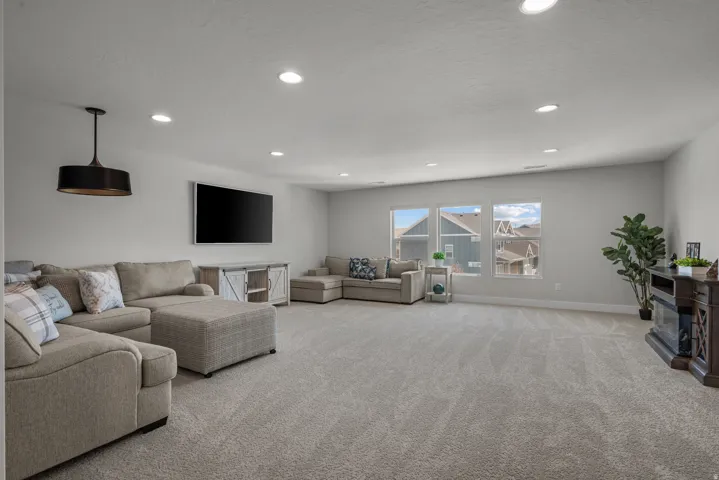 Spacious living area featuring light gray walls, recessed lighting, and a large triple window array