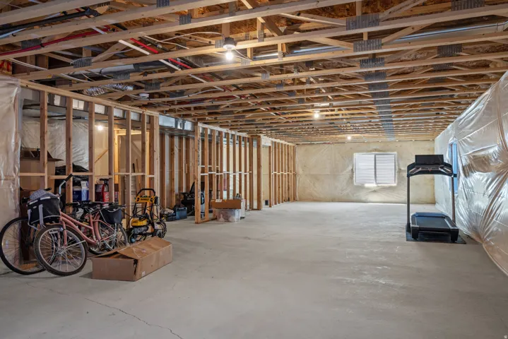 Unfinished basement featuring exposed wood joists, concrete flooring, framed interior walls, and visible utility lines