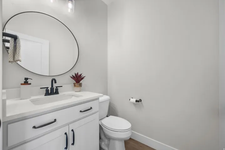 Bathroom vanity featuring a white countertop with integrated sink, matte black faucet, and white cabinetry with black hardware