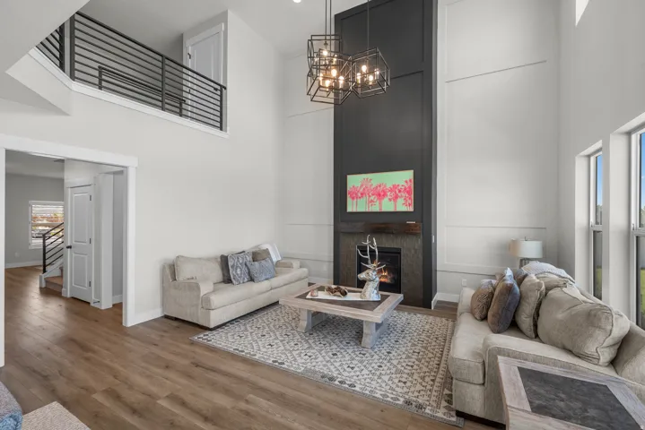 Two-story living area featuring a prominent fireplace with a dark-paneled surround, a wood mantel, and stone-look tiling