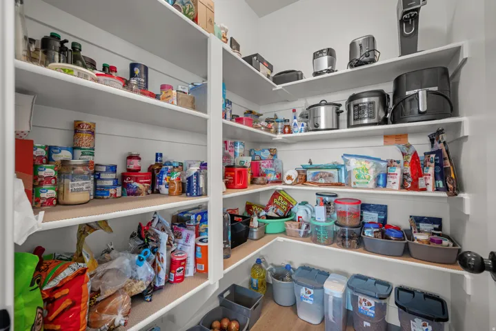 Built-in shelving providing extensive storage, white painted walls, and wood-finish flooring