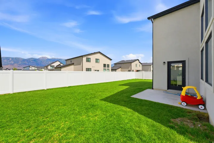 Expansive green lawn with a white privacy fence and a concrete patio